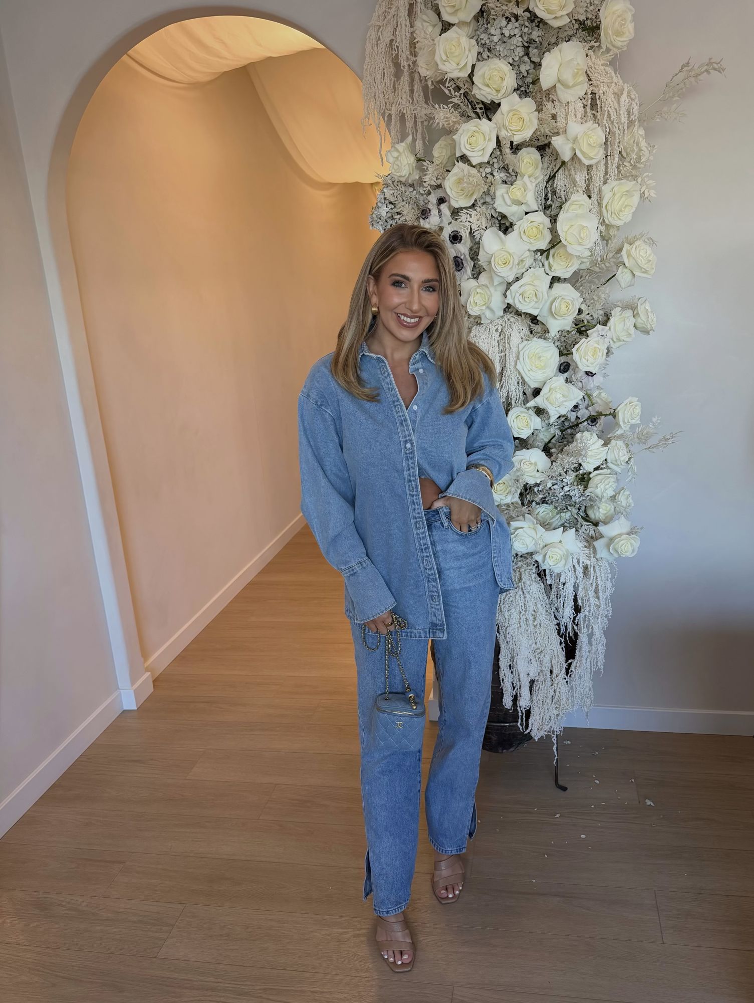 Alicia in denim beneath an arch of white roses